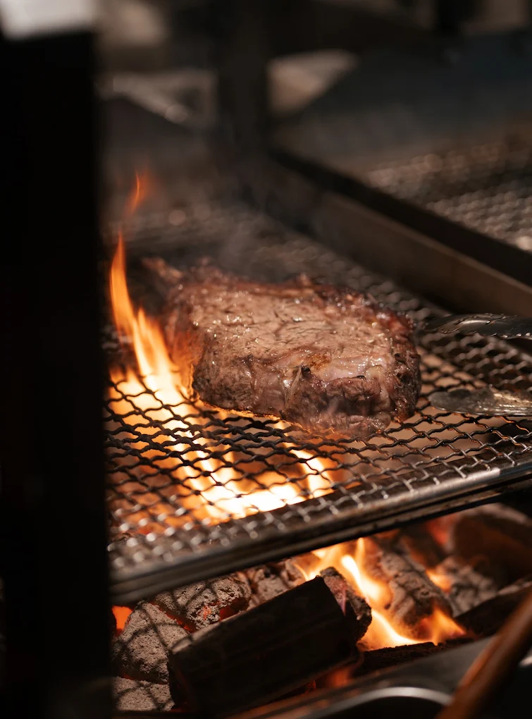 Wagyu steak searing over open charcoal fire at Vore Canggu